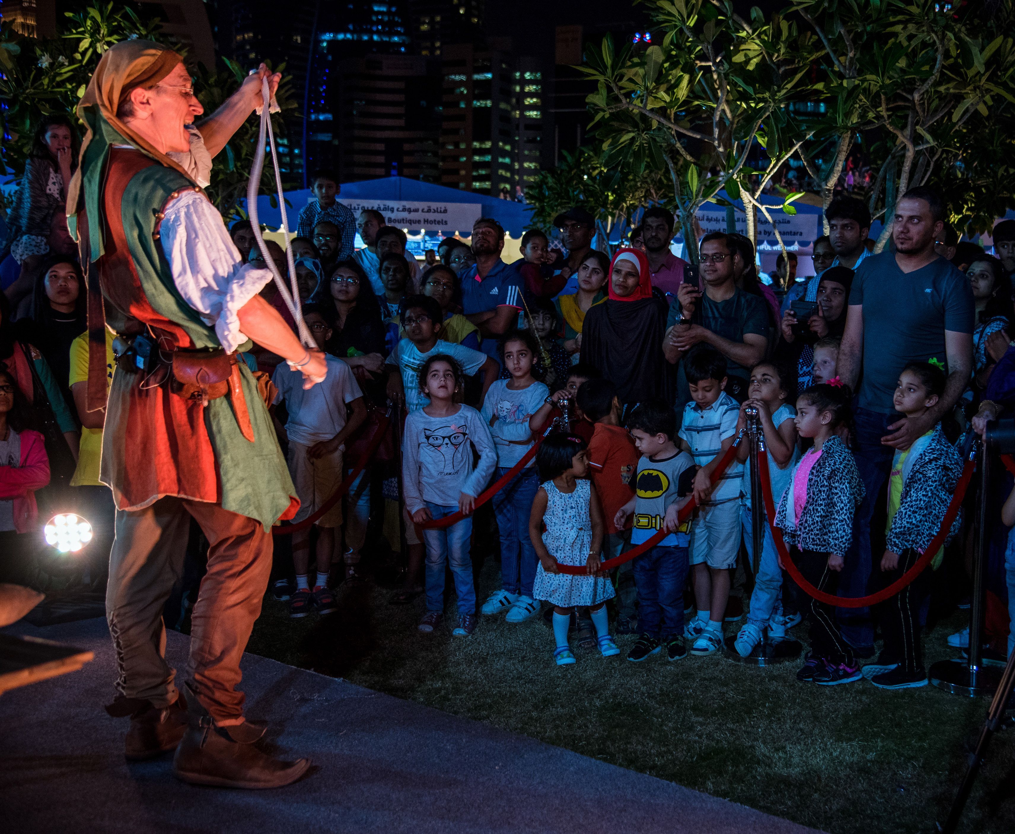 A German man wearing a medieval costume performs magic tricks for a crowd at Qatar International Food Festival.