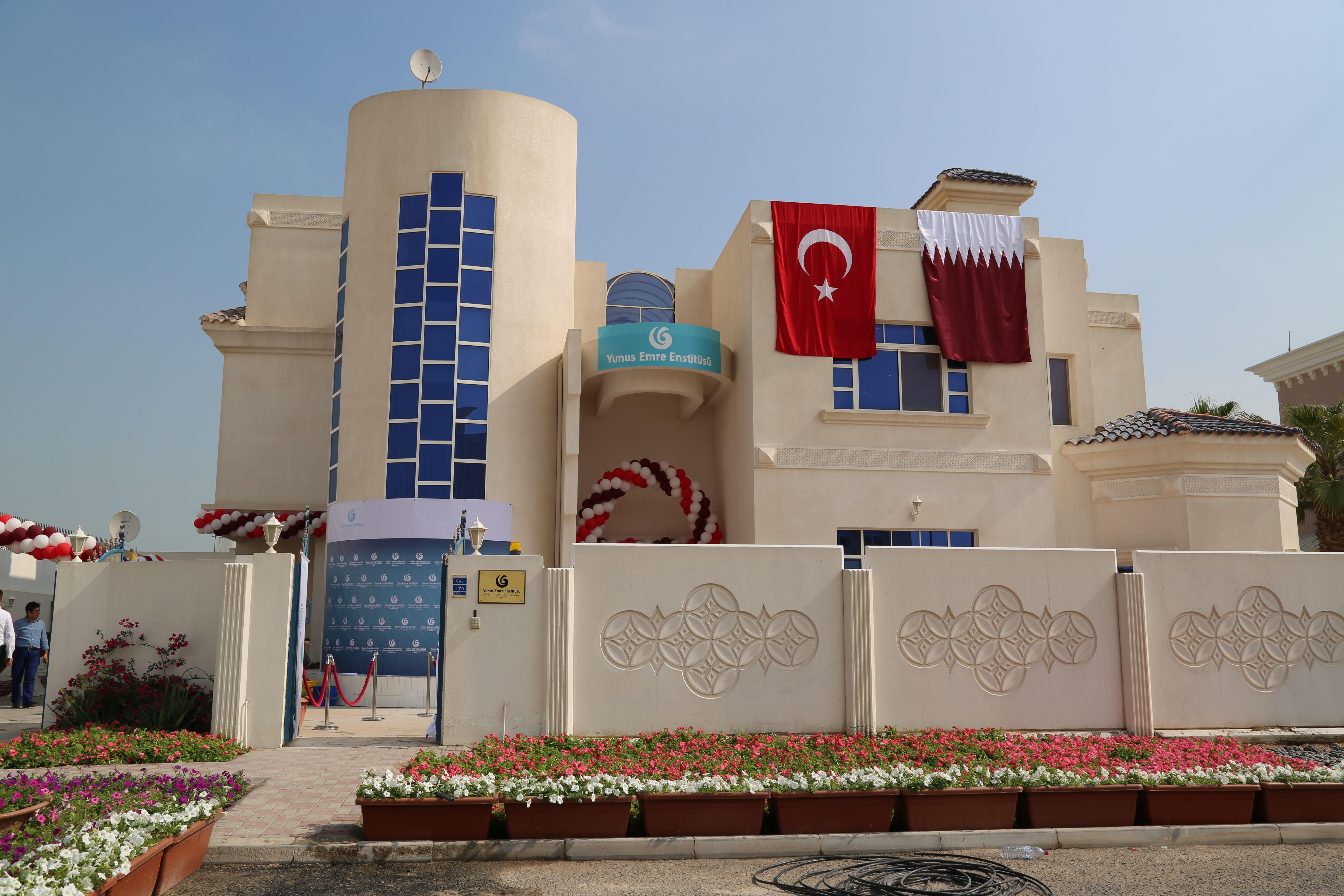 The light beige building of the Yunus Emre Cultural Centre, with the Turkish and Qatari flags hanging from the roof.
