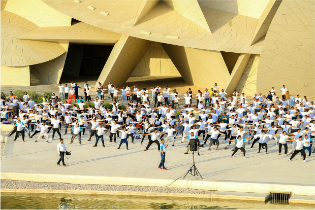 Several hundred people take part in an outdoor yoga class for International Yoga Day 2019 at the National Museum of Qatar.