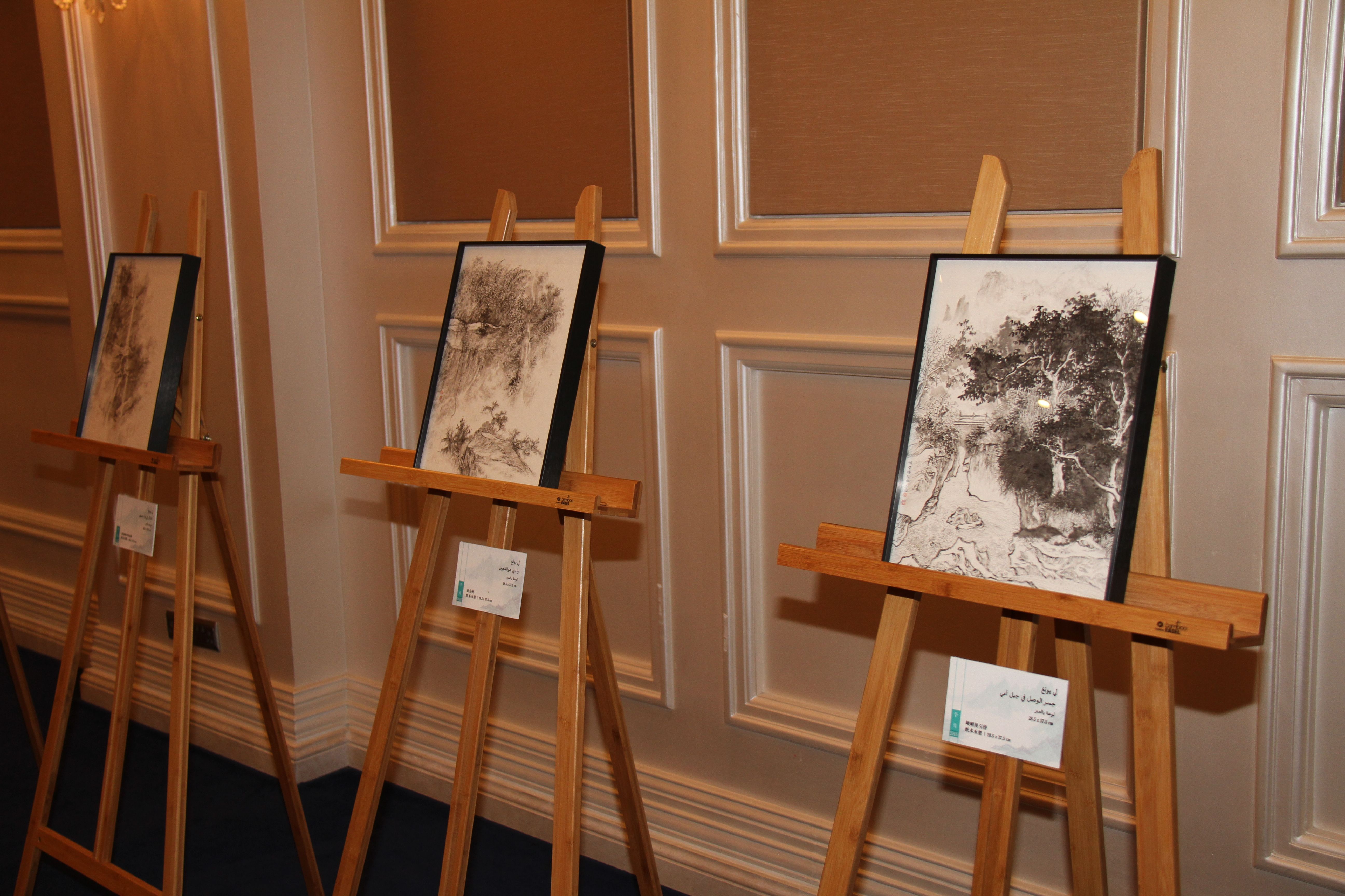 Three contemporary Chinese paintings on canvas are displayed on wooden easels during Qatar-China 2016.