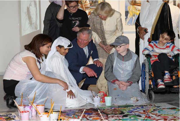 Prince Charles crouches down to the floor to speak with children during the Arts and Disability Festival for Qatar-UK 2013.