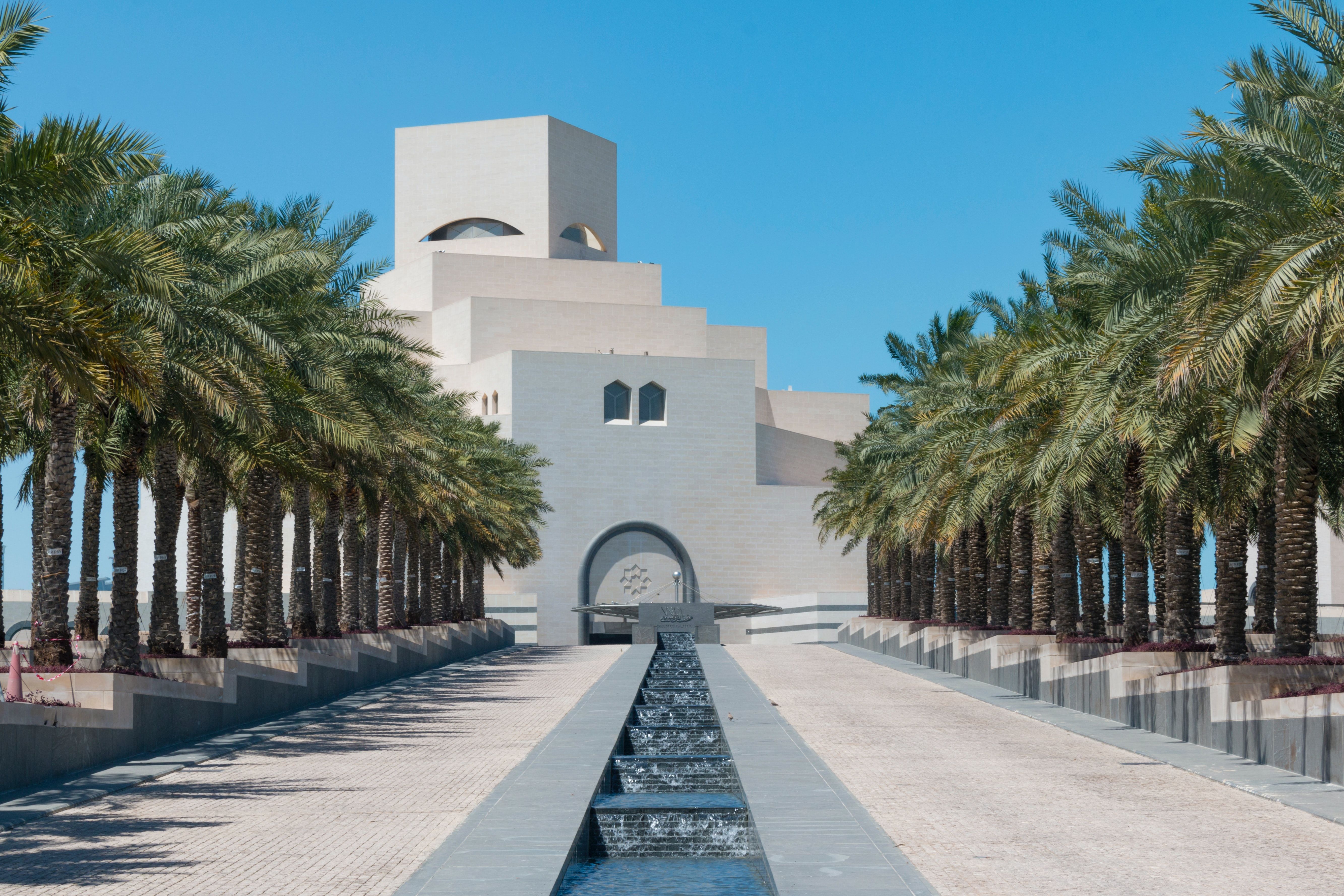 Shallow water feature lined with palm trees leading to the Museum of Islamic Art in Doha, designed by architect I.M. Pei.
