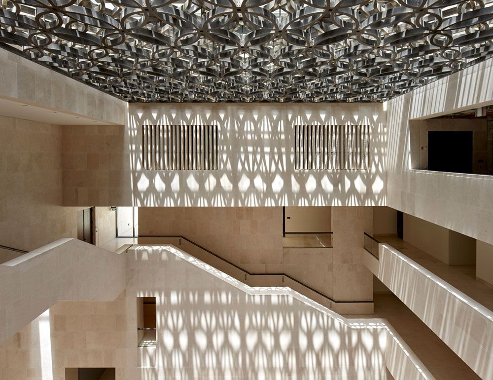 Elegant open-plan atrium in the M7 Cultural Hub with a stone stairway and dappled light from an Islamic patterned skylight.