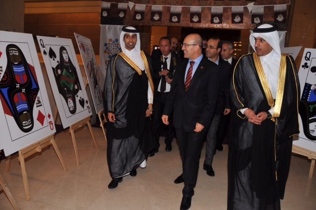 Important officials from Qatar and Turkey walk through an exhibition of oversized specially designed playing cards on easels.
