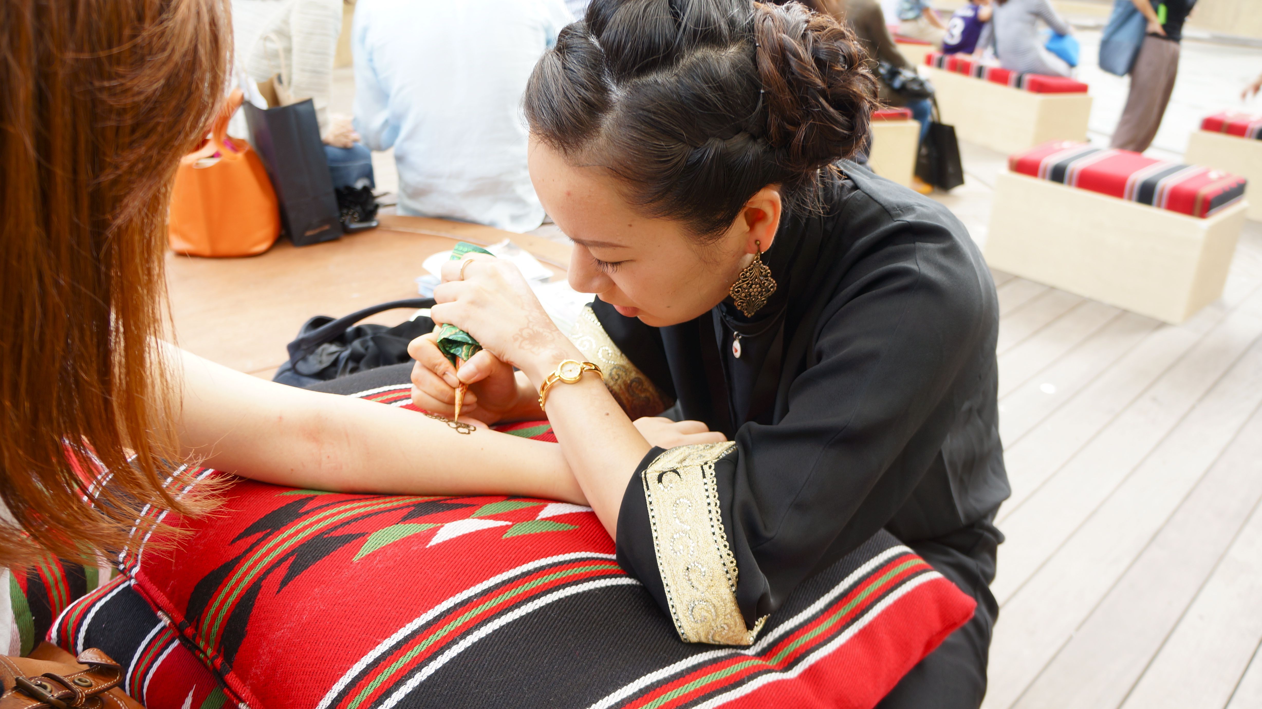 A Japanese woman draws a design on another woman's forearm during Ferjaan in Tokyo for the Qatar-Japan 2012 Year of Culture.