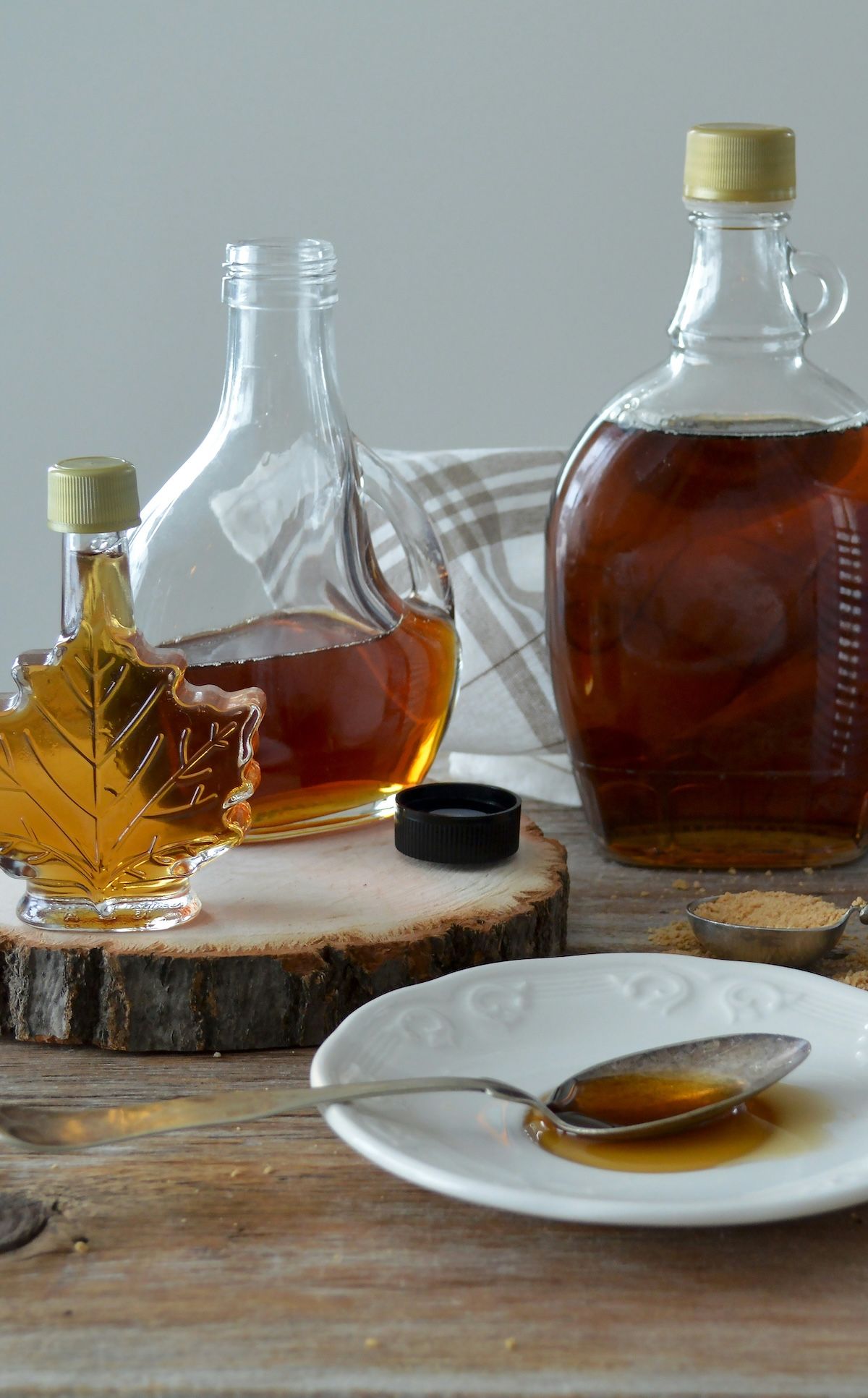 different bottles of maple syrup, with a spoon of maple syrup ready to be tasted