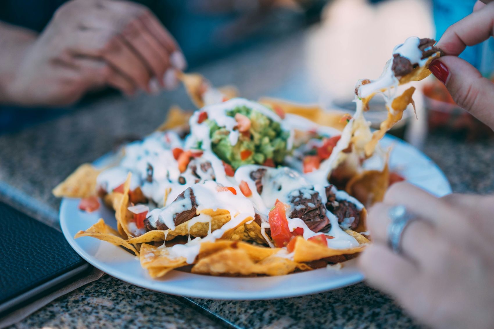 A plate of nachos, the most popular tex-mex dish, made of tortilla chips covered with melted cheese, guacamole and sour cream.