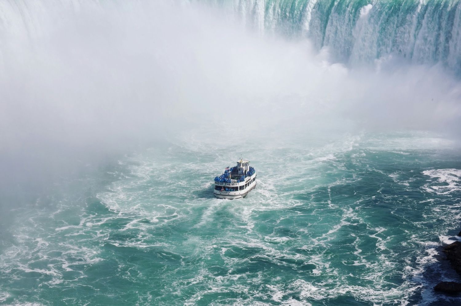 A close-up view of a boat from the Maid of the Mist tour approaching the base of the Horseshoe Falls at Niagara Falls.