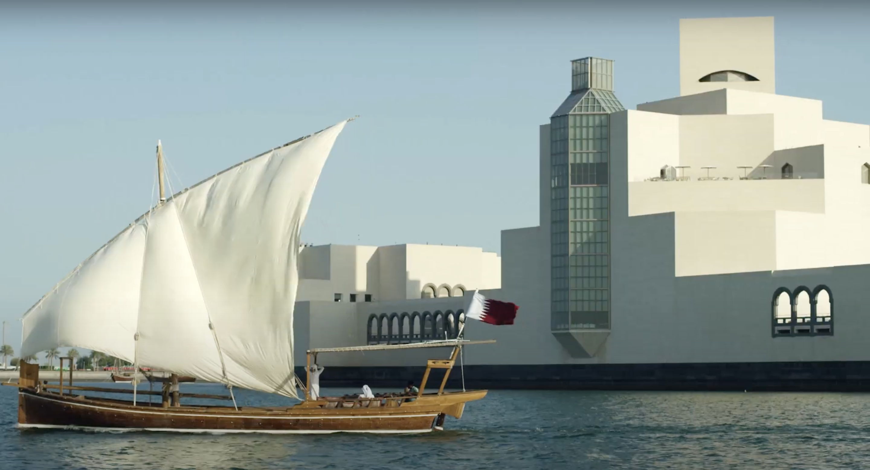 قارب شراعي خشبي تقليدي يبحر بجوار متحف الفن الإسلامي في الدوحة.