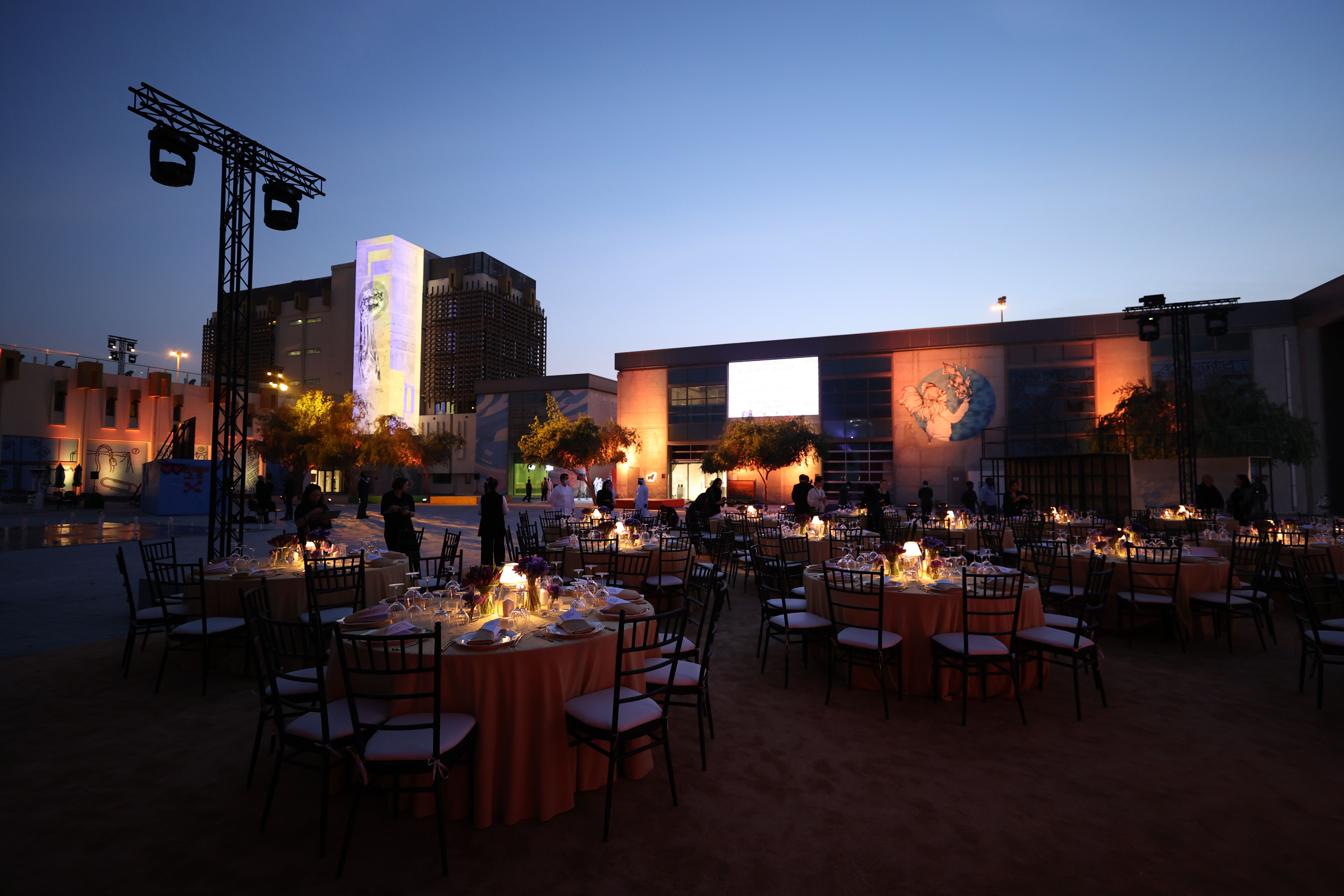 An outdoor courtyard at dusk, set up for the Years of Culture 2022 opening ceremony with round tables set for a formal dinner.An outdoor courtyard at dusk, set up for the Years of Culture 2022 opening ceremony with round tables set for a formal dinner.