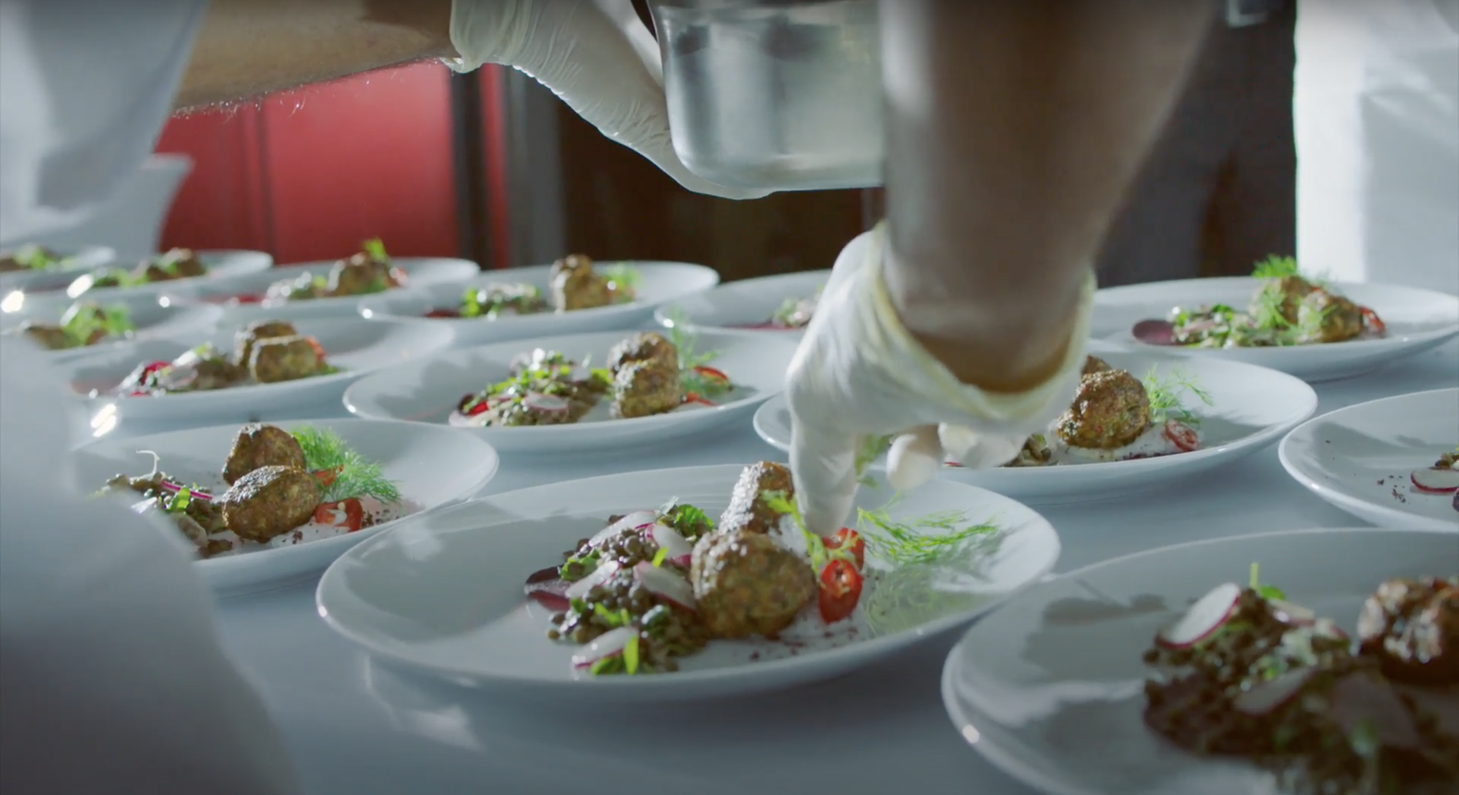 A chef's gloved hand adds the finishing touches to plated dishes, ready to be served at the Years of Culture opening ceremony