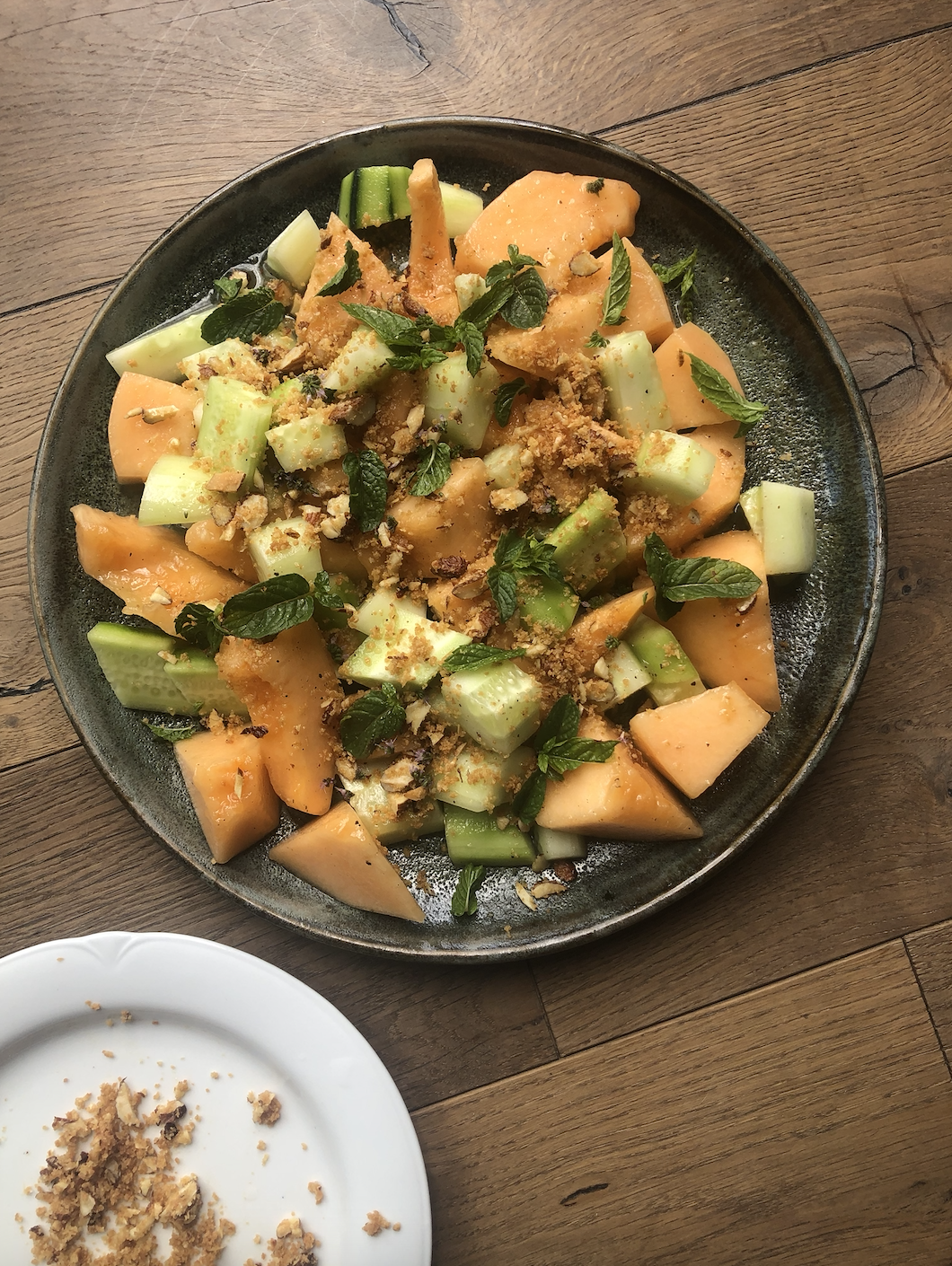 A plate of Melon and Cucumber Salad decorated with mint leaves and ground almonds, from a recipe by Sami Tamimi.