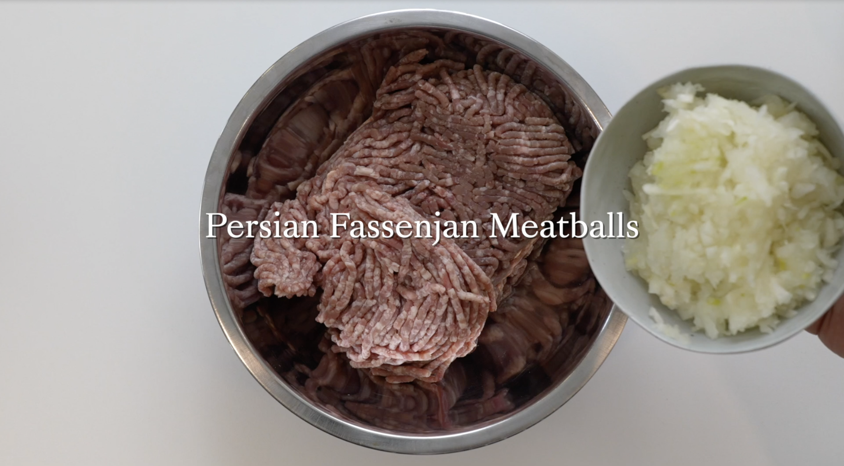A bowl of minced meat and a smaller bowl of chopped onions, for making Persian Fassenjan Meatballs