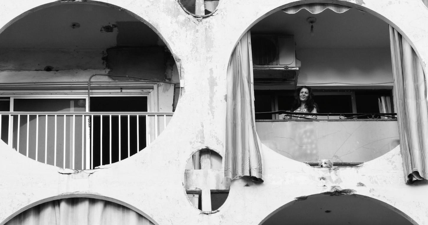 Black and white still of a woman on a circular balcony taken from Alessandra El Chanty's video of scenes from Beirut.