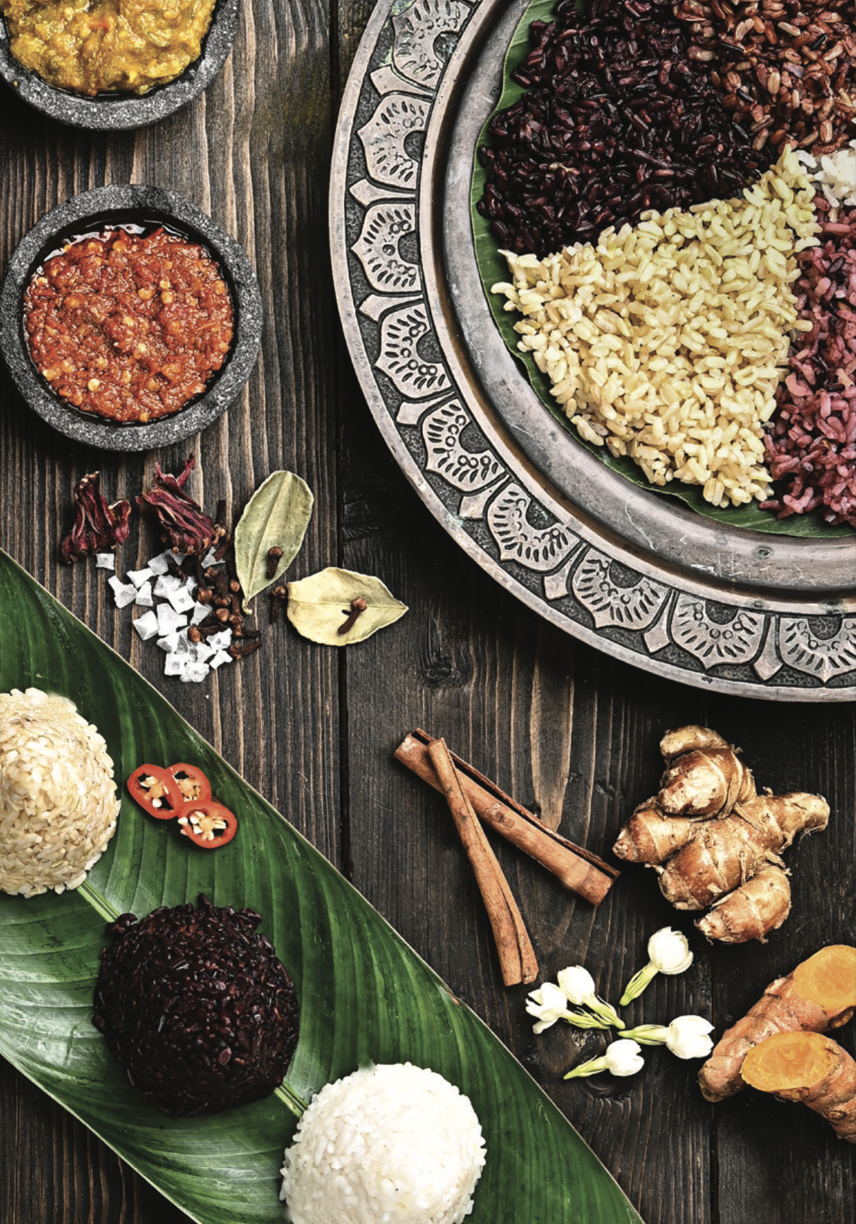 أطباق إندونيسية تشمل أنواعًا مختلفةً من الأرز والصلصات الملونة، تقدم على طاولة خشبية.