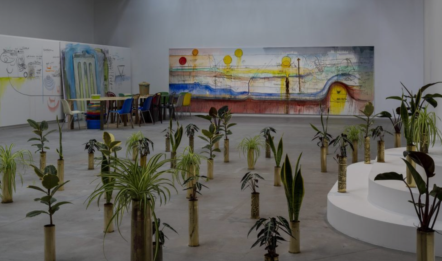 Gallery space with artwork and trees as part of the Our World is Burning Exhibition at Palais de Tokyo in Paris.
