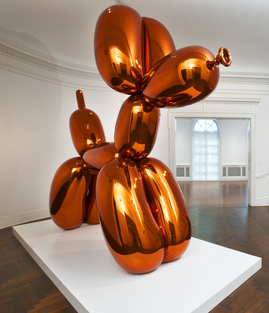 Large metallic orange sculpture of a balloon dog in a gallery space during Jeff Koons: Lost in America exhibition in Doha.