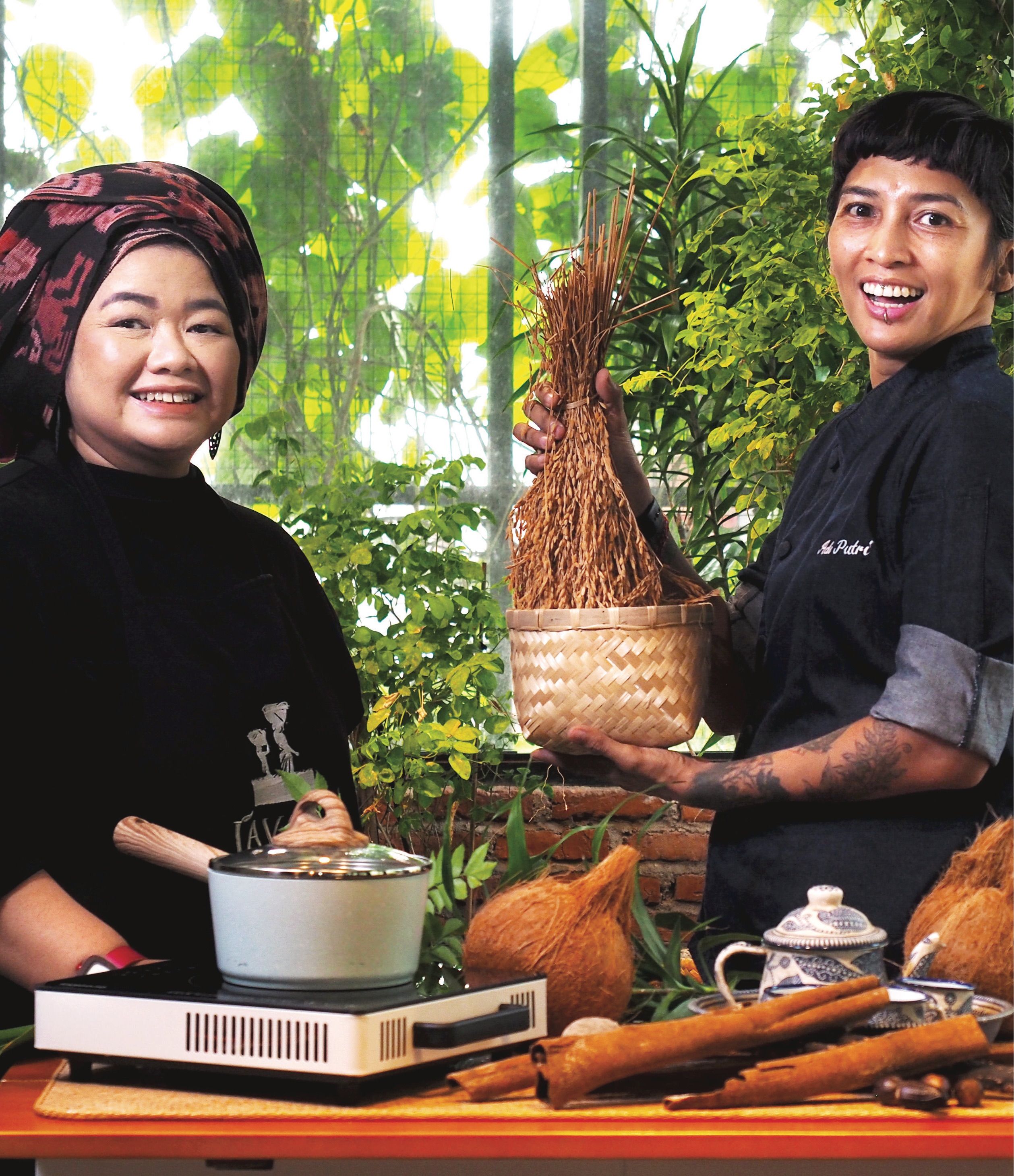 امرأتان ترتديان سترات الشيف تعدان الطعام بمكونات إندونيسية في مطبخ خارجي.