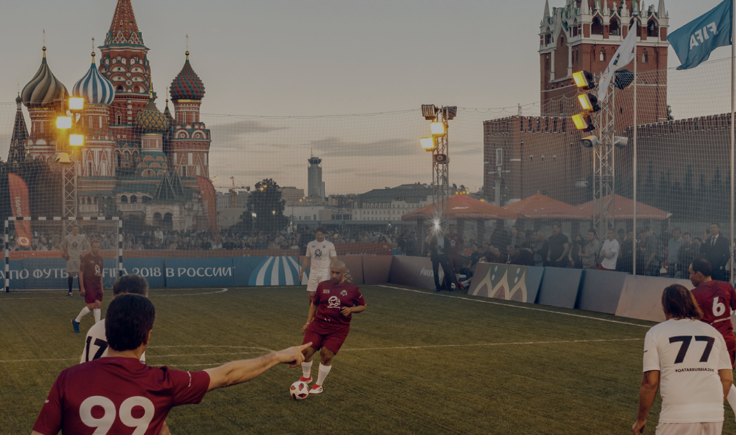 A football pitch with two opposing teams mid-match, with Moscow's famous Red Square in the background.