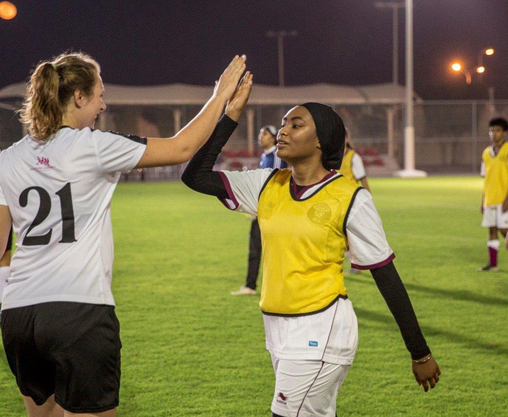 2 female football players high five each. other on the pitch during a friendly match between teams from Germany and Qatar. 